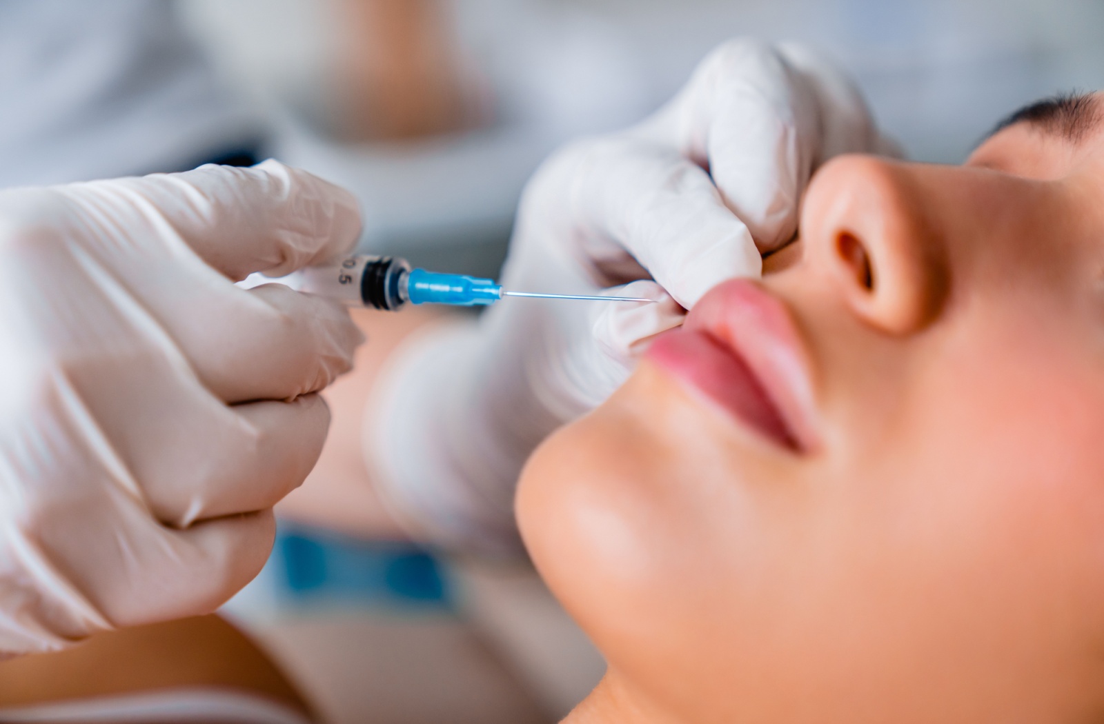 A close-up image of a dermatologist performing a Botox injection on their patient's lip.