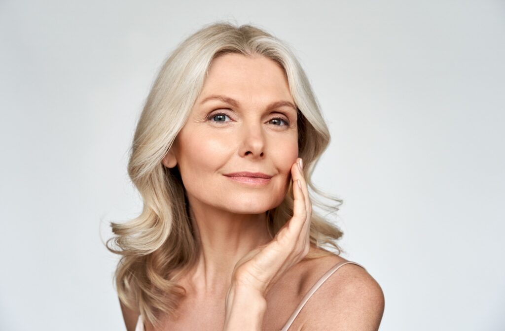 Woman in her 40's with smooth skin touching her face with her hand.